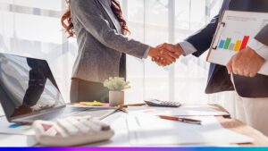 Parceria corporativa representada por aperto de mãos em ambiente de negócios com relatórios de crescimento e tecnologia.